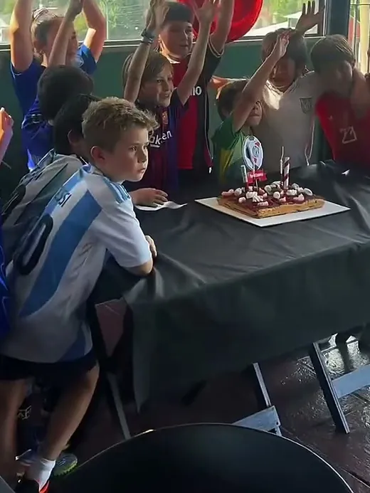 La torta de cumpleaños con las velitas prendidas y los chicos aplaudiendo