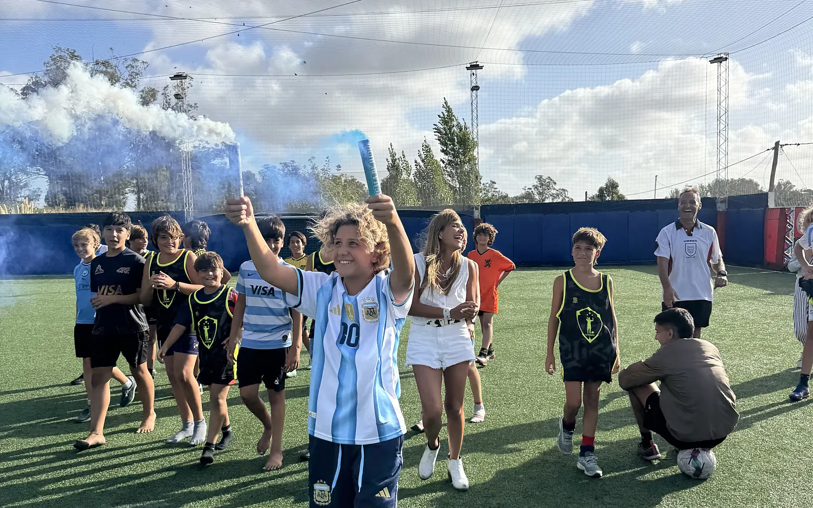Los chicos del cumple caminando por la cancha con bengalas de humo celeste